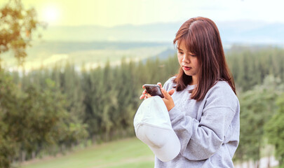 A beautiful Asian woman is texting on her mobile phone in the park.