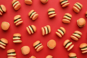 Tasty jelly candies in shape of burger on red background, flat lay