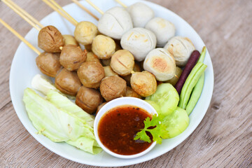 Asian Thai food grilled meatballs fishball and porkball with spicy sauce, Meatballs on skewers on white plate and fresh vegetables cabbage yard long bean cucumber