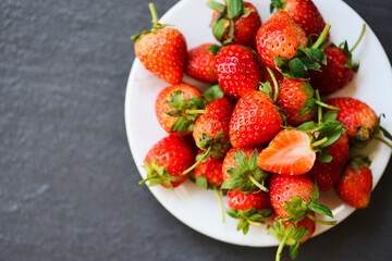 Fresh strawberries on white plate on the table, Red ripe strawberry on dark background