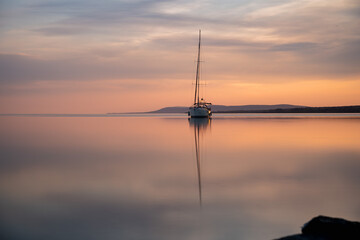 a sailing boat at sunset on a calm lake
