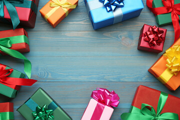 Frame of gift boxes on light blue wooden table, flat lay. Space for text