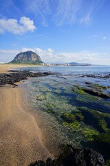 Fototapeta na wymiar a beautiful beach with mossy rocks and clear water