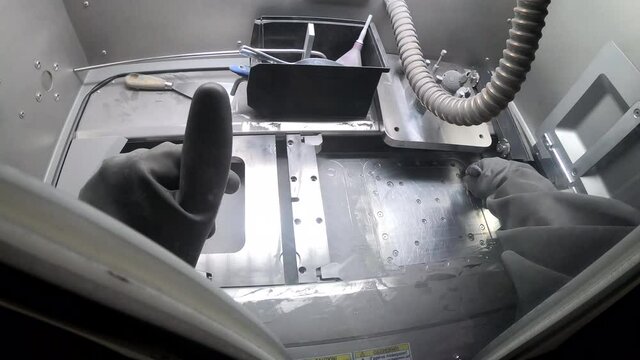 Male worker in rubber glove cleans printing platform inside 3d printer for metal