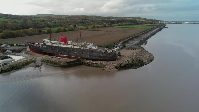 Moored huge vessel on sandy coast, aerial fly forward view