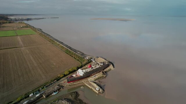 Rural landscape and TSS Duke of Lancaster vessel on sandy coast, aerial orbit view