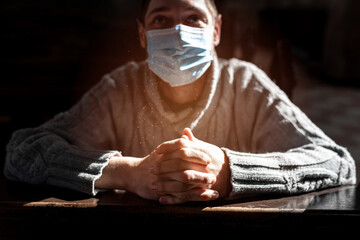 The masked man is praying in the church. Religious concept, light of spiritual state