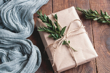 Gift box next to vintage tablecloth gray and green leaves on wooden brown table