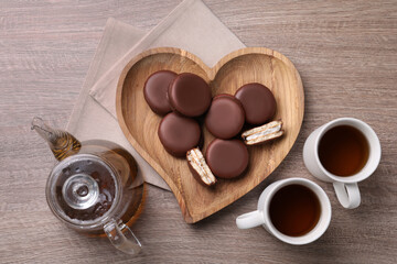 Tasty choco pies and tea on wooden table, flat lay
