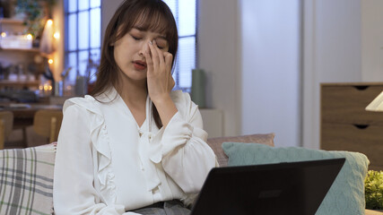 having blurred vision. Taiwanese businesswoman overworked on laptop in living room is rubbing her eyes. healthcare, authentic lifestyle