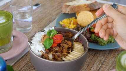 Digging up fresh vegan breakfast bowl. Granola with coconut, strawberry, banana, smoothie