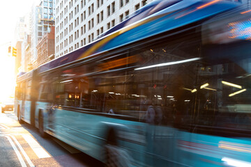 Fototapeta na wymiar New York City bus driving down the street through Manhattan with motion blur effect and sunlight background