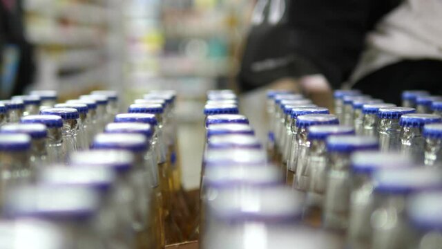 Hand with a ring of a customer taking couple bottles of beer from the row 