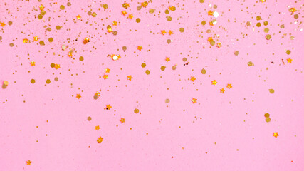 Festive Golden star sprinkles on pink background.