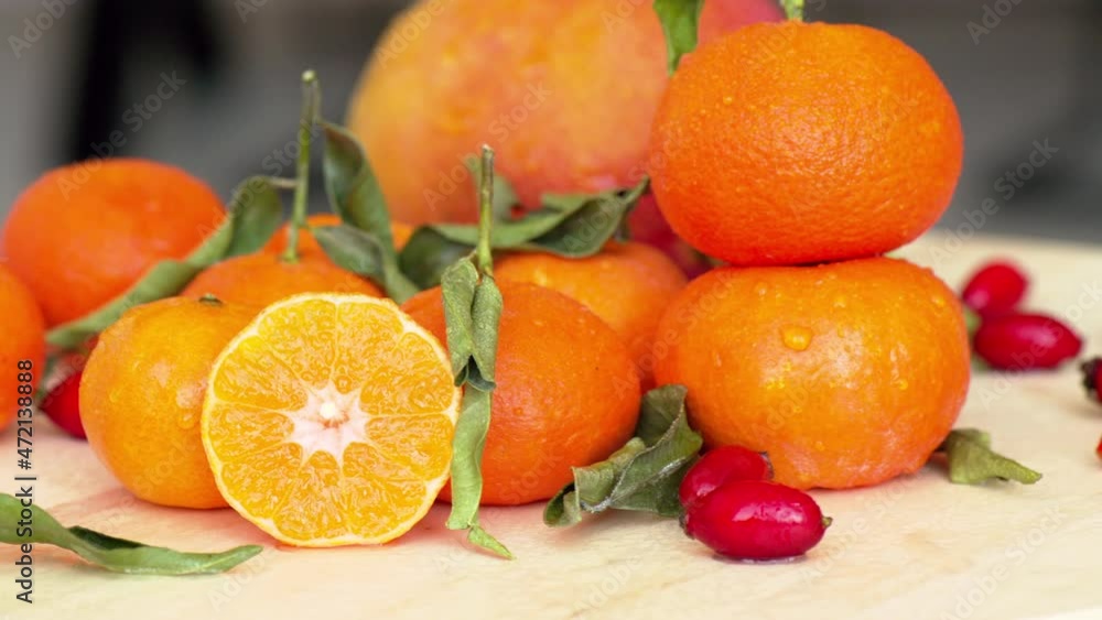 Wall mural Composition with oranges, mango, rosehip and green leaves, close up