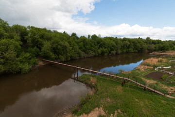 top view of a small wooden bridge over the river near the village near the forest