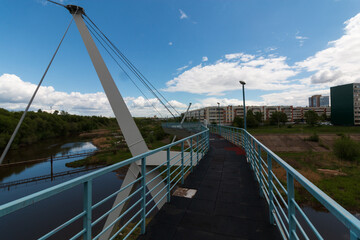 Fototapeta na wymiar pedestrian bridge over the river in summer in the city