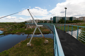 pedestrian bridge over the river in summer in the city