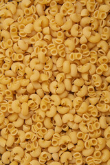 pasta concept the large amounts of dry yellow tubular-shaped short-cut macaroni pasta sorted together