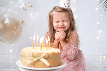 Obraz na płótnie Canvas cute little child girl blowing candles on birthday cake and celebrating birthday