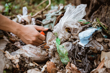 hand picking up plastic waste and put in the trash bag