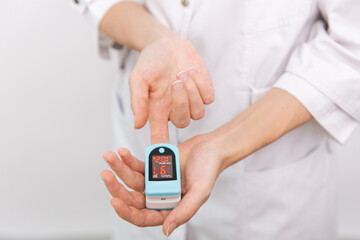Pulse oximeter with hand of doctor isolated on white. The concept of portable digital device to measure person's oxygen saturation. Measuring oxygen saturation, pulse rate and oxygen levels