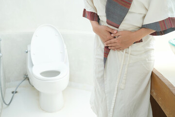 Abdominal pain woman holds her stomach with her hand. She has stomachache from diarrhea. Constipation concept. bathroom toilet background