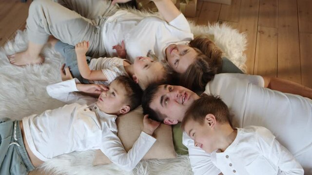 Top view at happy smiling family together lying on floor, loving hugs, embraces