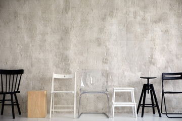 Wooden plastic and metal chairs placed in row near cement wall in studio