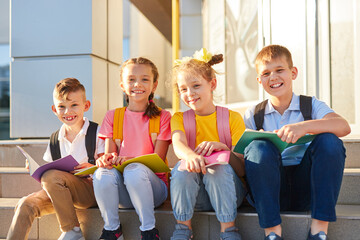 Cheerful kids with textbooks on stairs