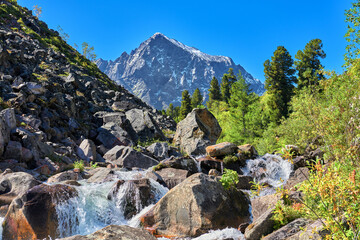 Alpine landscape with a cascade of water on a mountain stream