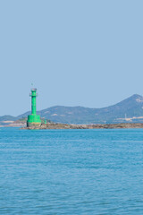 Green lighthouse on sandbar in port
