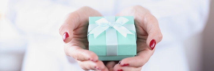 Small turquoise gift box in female hands closeup