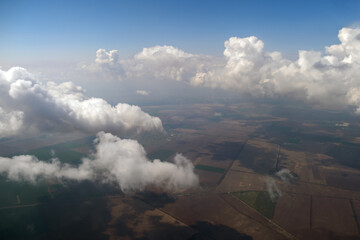 Aerial view from airplane window of white puffy clouds on bright sunny day