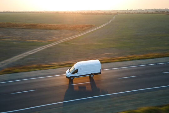 Aerial view of blurred fast moving cargo van driving on highway hauling goods. Delivery transportation and logistics concept
