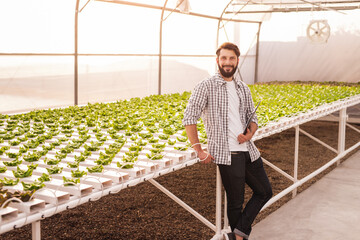 Smiling farmer in greenhouse with plants