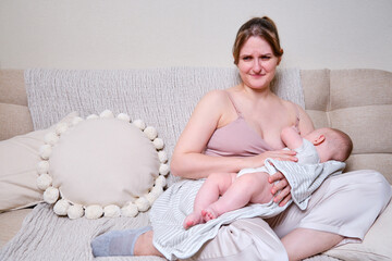 Pain and problems in a woman while breastfeeding a baby. Mother experiences discomfort while...