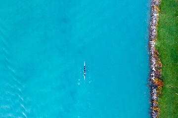 Four rowers passing the shoreline of Belle Isle Park in the Detroit River. 