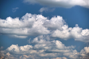 Bright landscape of white puffy cumulus clouds on blue clear sky
