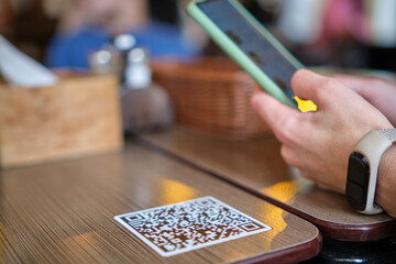 Closeup of guest hand ordering meal in restaurant while scanning qr code with mobile phone for...