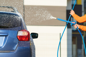 Closeup of male driver washing his car with contactless high pressure water jet in self service car wash