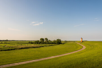 Deichlandschaft am Pilsumer Leuchtturm mit Windturbinen am Horizont, Pilsum, Krummhörn, Ostfriesland, Niedersachsen, Deutschland