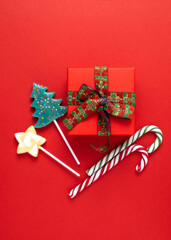 New Year's card, poster, creative. lollipop, a gift on a red background.