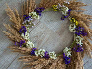 Creative autumn wreath with dried pampas grass and wildflowers on wooden background. space for...