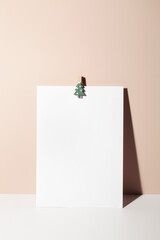 paper card note with paper clip in form of Christmas tree on beige background. copy space. new year minimal concept. greeting card for text