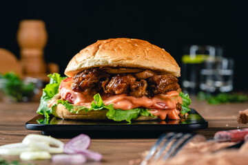 Fresh tasty chicken teriyaki burger on wood table. Sandwich with chicken burger, tomatoes, pickled...