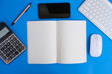 Blank notebook, a pencil, and space are on top of a blue office desk table. Flat lay, top view education concept