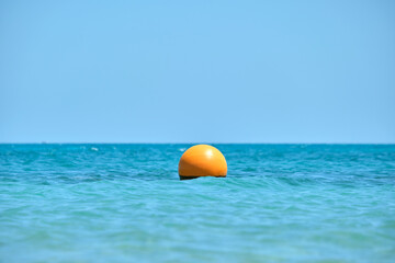 Orange buoy floating on sea surface waves. Human life safety concept