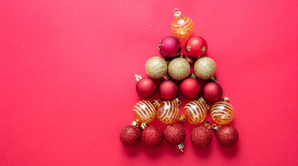 Christmas balls forming Xmas tree on empty red background. Greeting card template copy space.