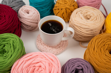 Close-up of multicolored cotton skeins and a mug of black coffee